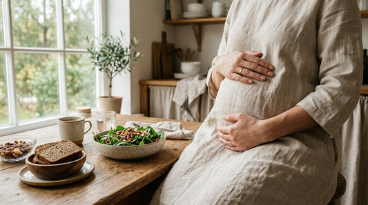Gravid kvinnas händer vid ett bord med grönsaker, nötter och fullkornsbröd som ger magnesium.